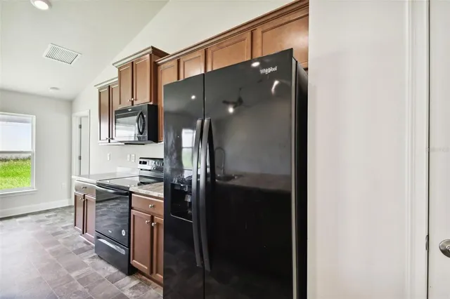 a kitchen with stainless steel appliances granite countertop a sink a stove and a wooden cabinets