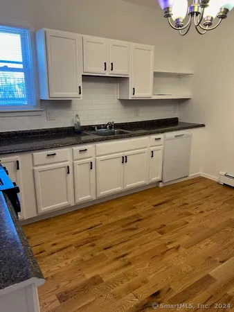 a kitchen with granite countertop white cabinets and wooden floor