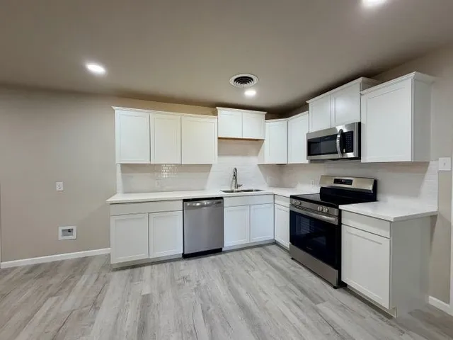 a kitchen with granite countertop a stove top oven sink and cabinets