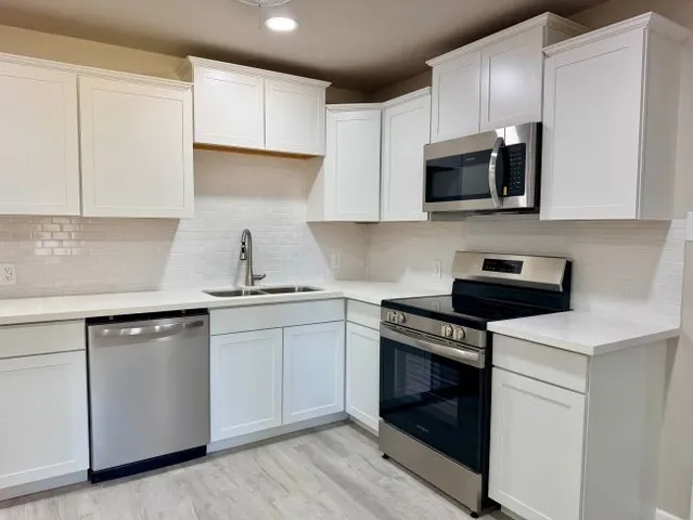 a kitchen with white cabinets and stainless steel appliances