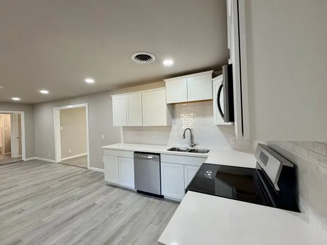 a kitchen with a sink a refrigerator and cabinets
