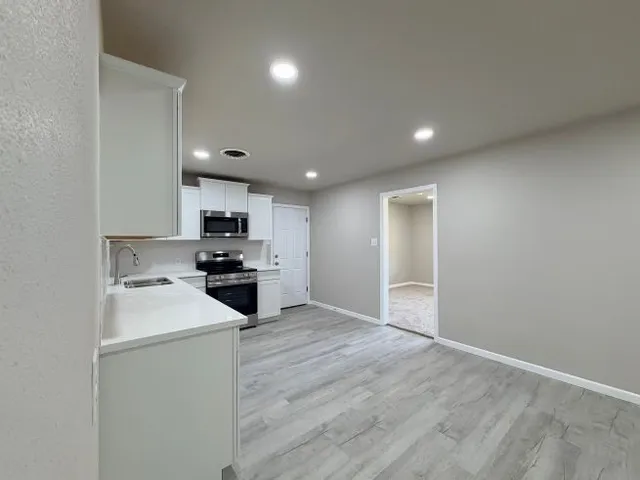 a kitchen with a sink a stove top oven and white kitchen