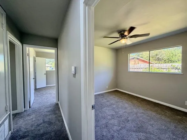 an empty room with windows and a chandelier fan