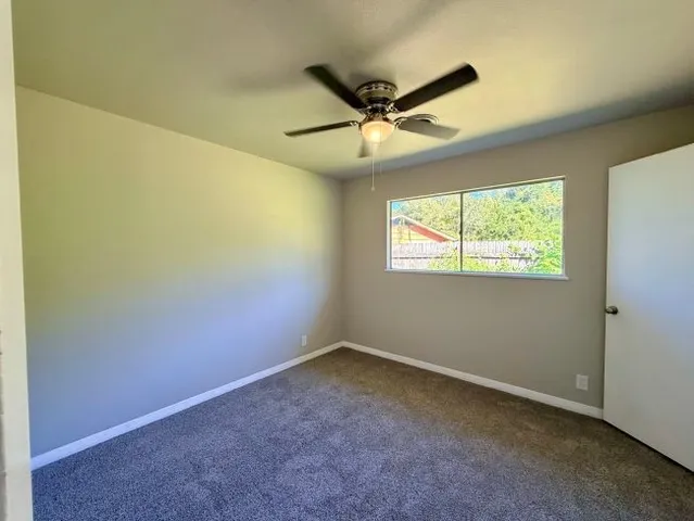 an empty room with windows and fan