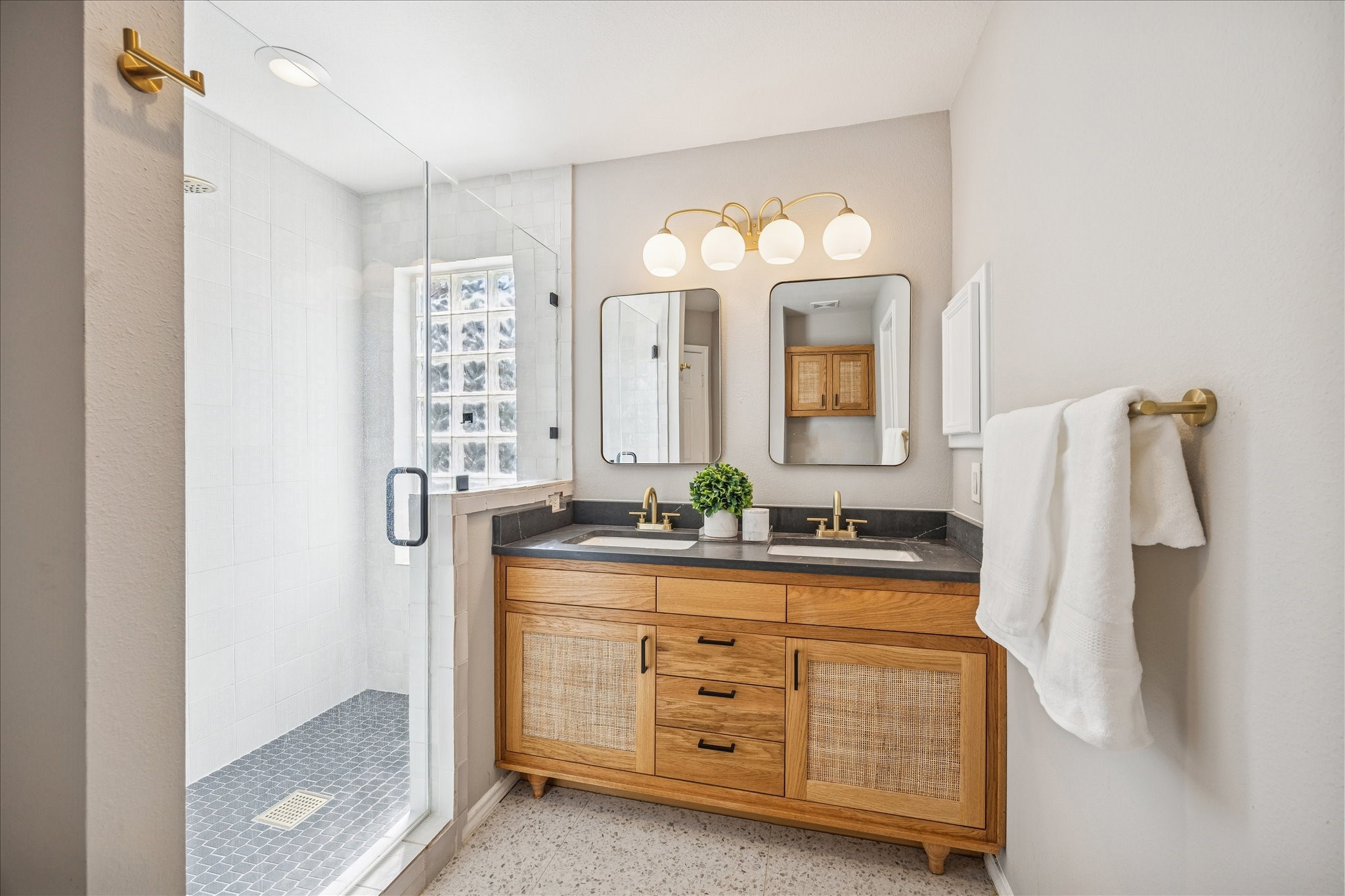 2607 Link Road Houston, TX 77009 - Photo 17 of 21 Primary Bathroom features a modern, spacious design with a glass-enclosed shower, dual sinks with a sleek wooden vanity, stylish lighting, and neutral tones, creating a serene and functional space.