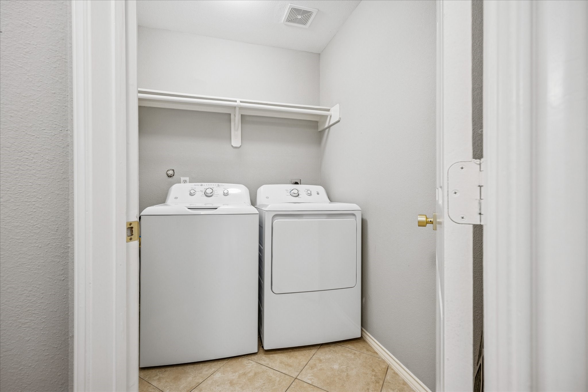 2607 Link Road Houston, TX 77009 - Photo 20 of 21 Compact Laundry Room with tile flooring, featuring a washer and dryer set under a single shelf for storage.
