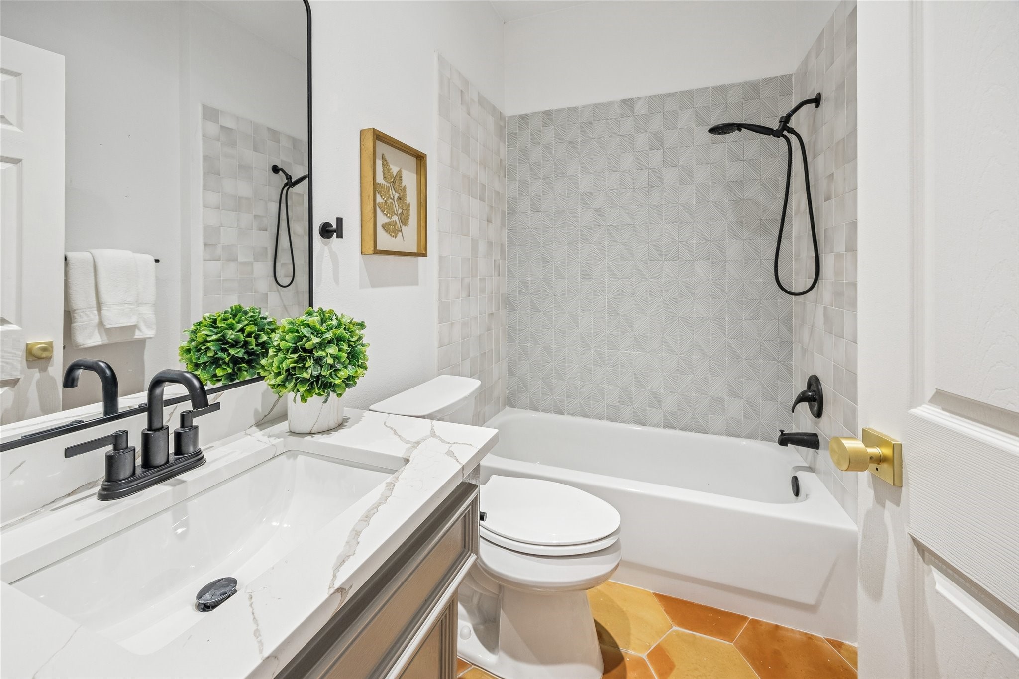 2607 Link Road Houston, TX 77009 - Photo 6 of 21 First floor en-suite Bathroom features a modern design with a sleek vanity, black fixtures, and a marble countertop. The shower area has textured tiles, and the space is accented with warm lighting, creating a clean and inviting atmosphere.
