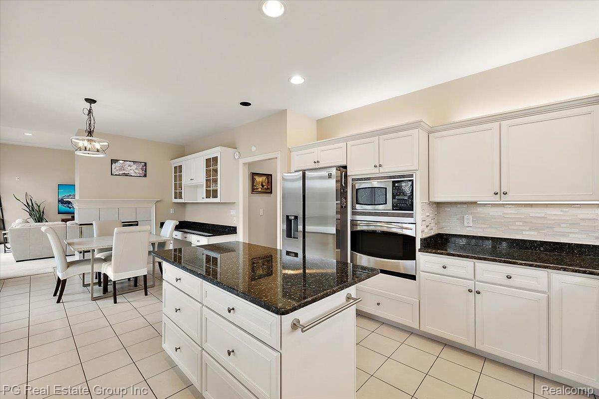 3571 Cedar Brook Drive Rochester, MI 48309 - Photo 28 of 57 Kitchen with stainless steel appliances, dark stone countertops, white cabinetry, a center island, and light tile patterned floors