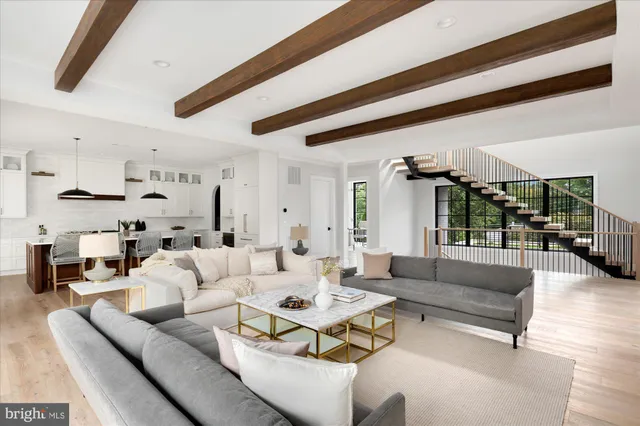 a living room with stainless steel appliances kitchen island granite countertop a stove a sink dishwasher and white cabinets with wooden floor