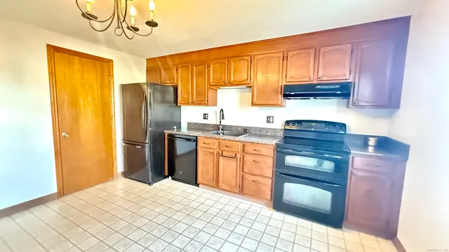 a kitchen with stainless steel appliances granite countertop a refrigerator a sink dishwasher a stove with wooden cabinets and floor