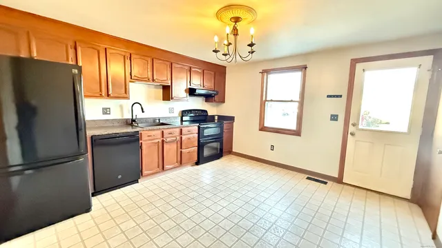 a kitchen with stainless steel appliances granite countertop a refrigerator a sink dishwasher a stove with white cabinets and wooden floor