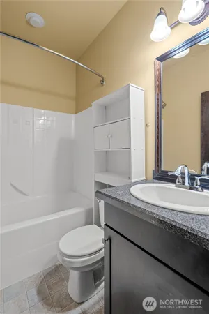 a bathroom with a granite countertop bathtub sink vanity mirror and toilet