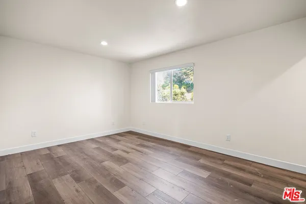 an empty room with wooden floor and window