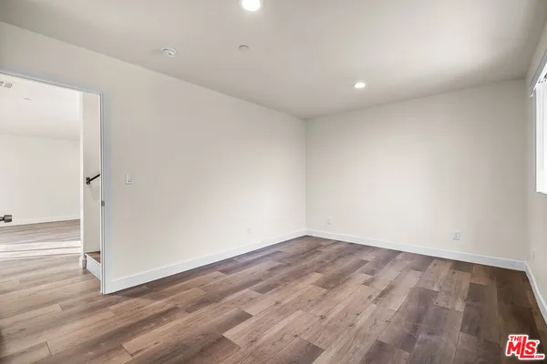 an empty room with wooden floor and entrance