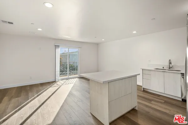 a view of a kitchen with a sink and dishwasher a stove top oven with wooden floor