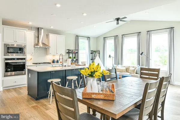 a kitchen with kitchen island granite countertop a stove a sink a refrigerator and white cabinets with wooden floor