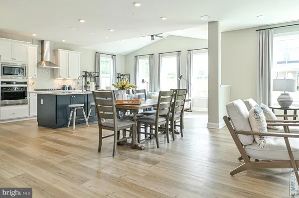 a kitchen with stainless steel appliances kitchen island granite countertop a sink a stove a refrigerator and white cabinets with wooden floor