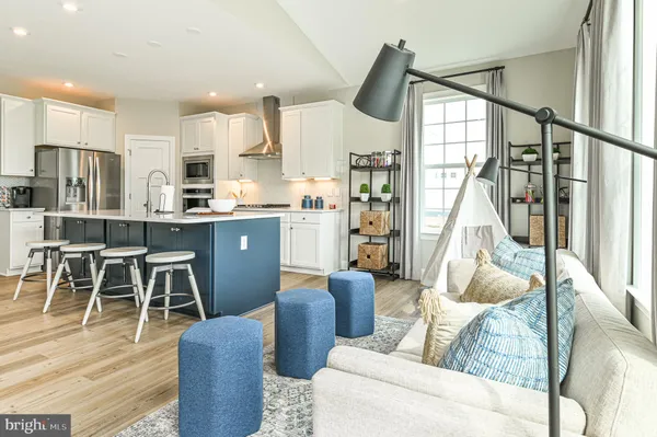 a living room with furniture kitchen view and a wooden floor