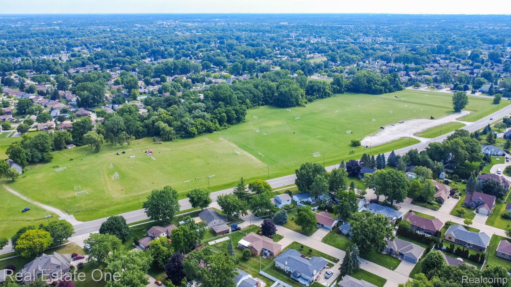 13912 Clinton River Road Sterling Heights, MI 48313 - Photo 43 of 43 Expansive green space bordered by mature trees and residential properties, featuring multiple sports fields and paved roads