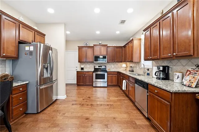 a kitchen with stainless steel appliances granite countertop a refrigerator a sink a stove top oven and a center island