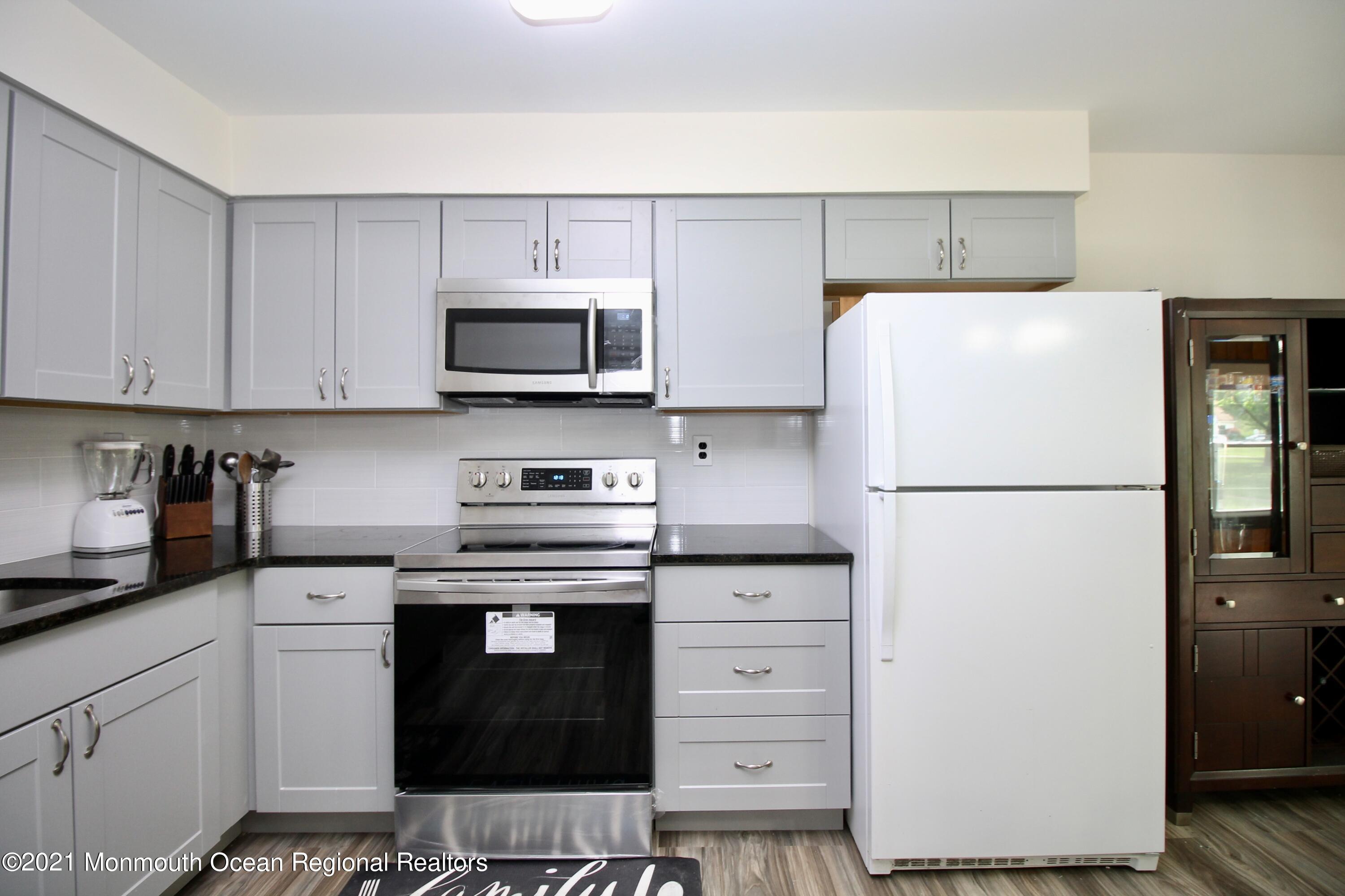152 Cours De Pasteur, Unit E Freehold, NJ 07728 - Photo 8 of 21 a kitchen with stainless steel appliances white cabinets and a refrigerator