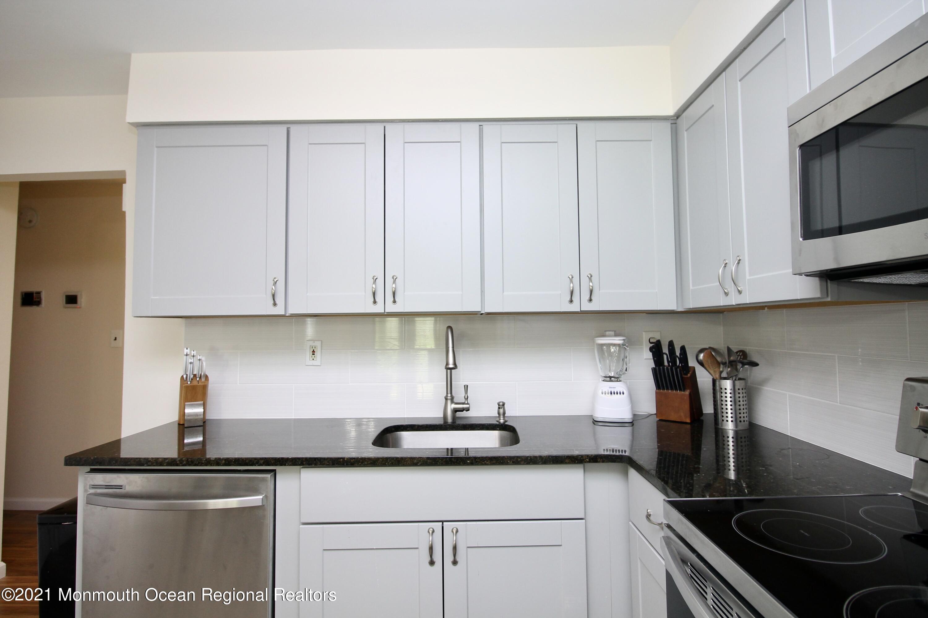 152 Cours De Pasteur, Unit E Freehold, NJ 07728 - Photo 9 of 21 a kitchen with stainless steel appliances granite countertop white cabinets a sink and dishwasher