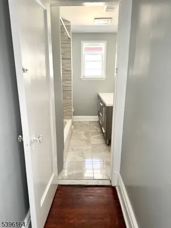 a view of a hallway with wooden floor and a bathroom