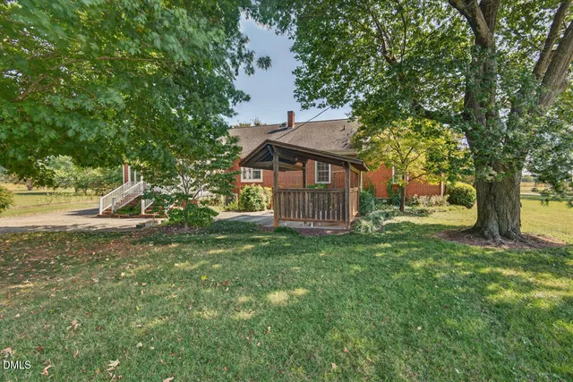 a backyard of a house with plants and a large tree