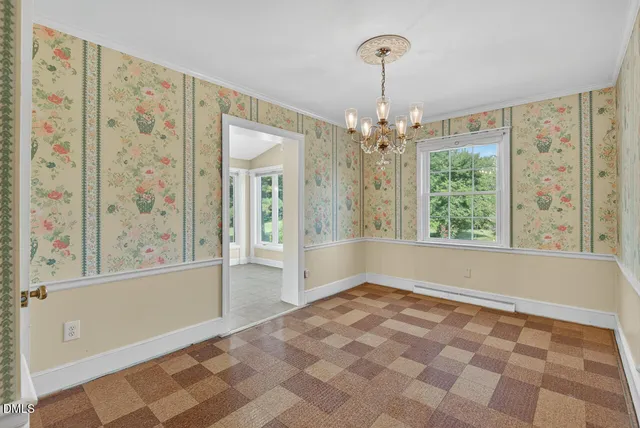 an empty room with wooden floor chandelier fan and windows
