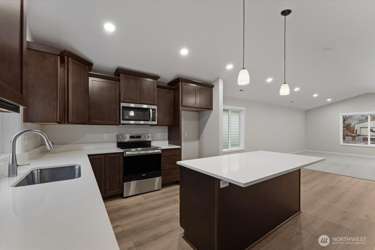 34 Simpson Street Mansfield, WA 98830 - Photo 13 of 29 a large kitchen with kitchen island a stove a sink a refrigerator and island
