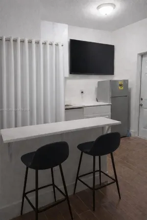 a kitchen with a table chairs and a flat screen tv