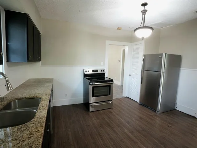a kitchen with granite countertop a refrigerator and a stove top oven
