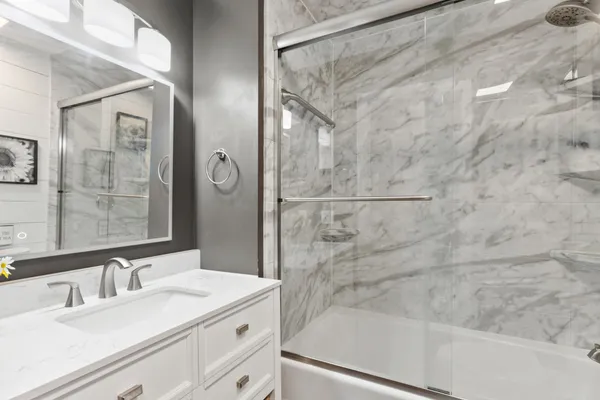 a bathroom with a granite countertop sink a mirror and shower