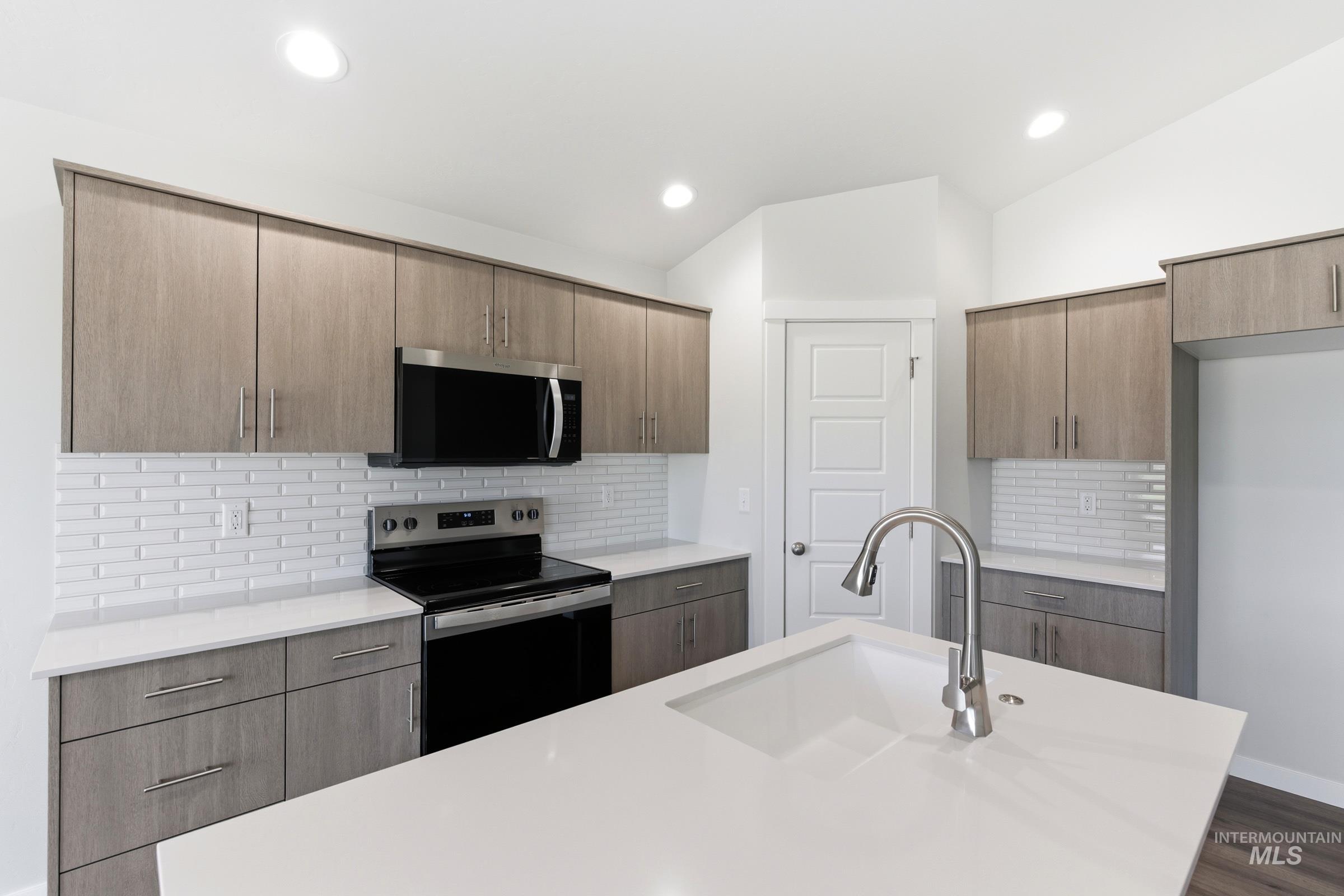 1059 West Jasper Street Meridian, ID 83642 - Photo 6 of 23 Contemporary kitchen featuring light wood-finish cabinetry, white subway tile backsplash, and sleek stainless steel appliances