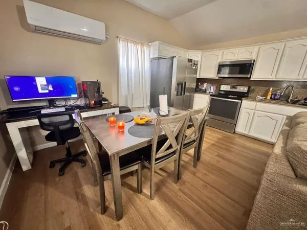 a kitchen with a refrigerator a stove a microwave oven a dining table and chairs with wooden floor