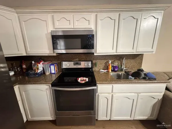 a kitchen with white cabinets and black appliances