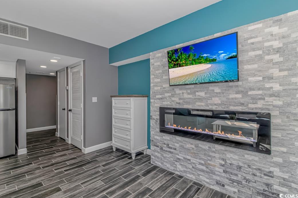 1605 South Ocean Boulevard, Unit 603 Myrtle Beach, SC 29577 - Photo 10 of 40 Unfurnished living room featuring a glass covered fireplace and wood tiled floors
