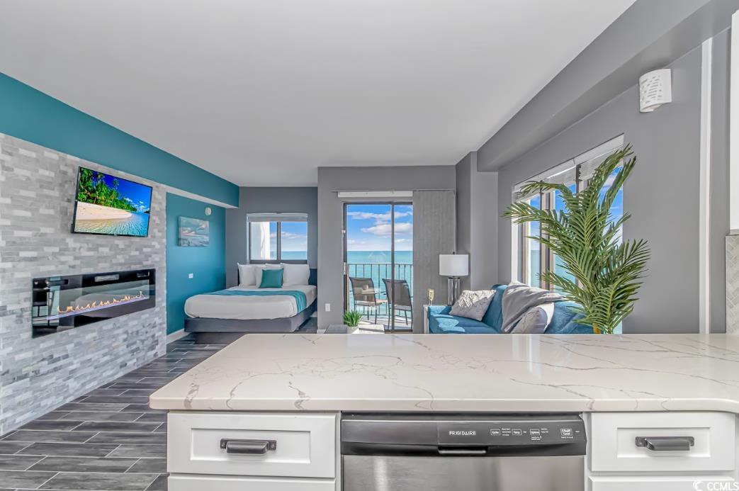 1605 South Ocean Boulevard, Unit 603 Myrtle Beach, SC 29577 - Photo 39 of 40 Kitchen featuring open floor plan, stainless steel dishwasher, light stone countertops, wood finish floors, and white cabinetry