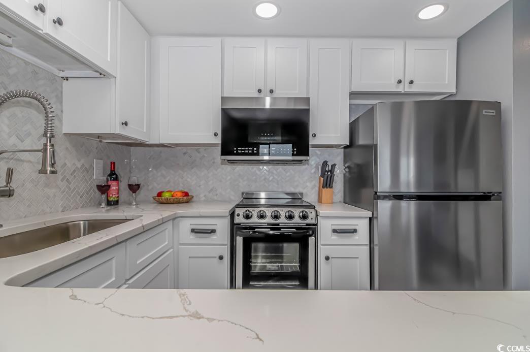 1605 South Ocean Boulevard, Unit 603 Myrtle Beach, SC 29577 - Photo 17 of 40 Kitchen featuring stainless steel appliances, tasteful backsplash, white cabinetry, and recessed lighting