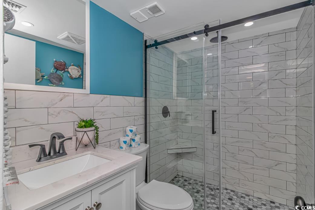 1605 South Ocean Boulevard, Unit 603 Myrtle Beach, SC 29577 - Photo 19 of 40 Bathroom with vanity, tile walls, a stall shower, and recessed lighting