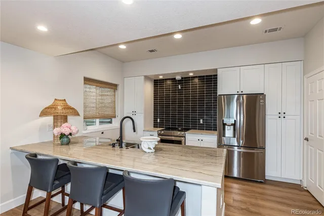 a kitchen with stainless steel appliances granite countertop a dining table chairs and refrigerator