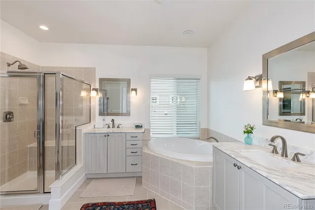 a bathroom with a granite countertop sink a bathtub a mirror a vanity and shower