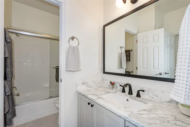 a bathroom with a granite countertop sink mirror toilet and bathtub