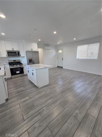 a large white kitchen with wooden floors and white stainless steel appliances
