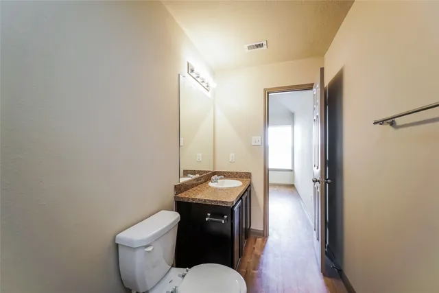 a bathroom with a granite countertop toilet a sink and a mirror