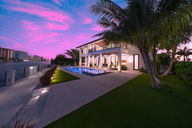 a view of a big house with a yard and wooden fence