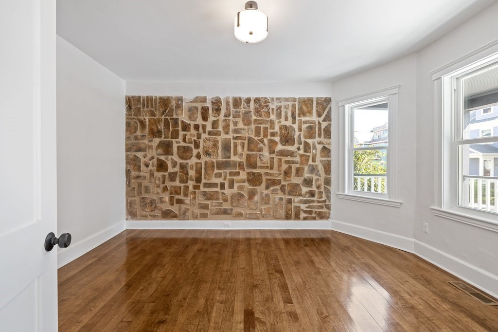 21 Alpha Road, Unit 1 Boston, MA 02124 - Photo 16 of 24 an empty room with wooden floor and windows