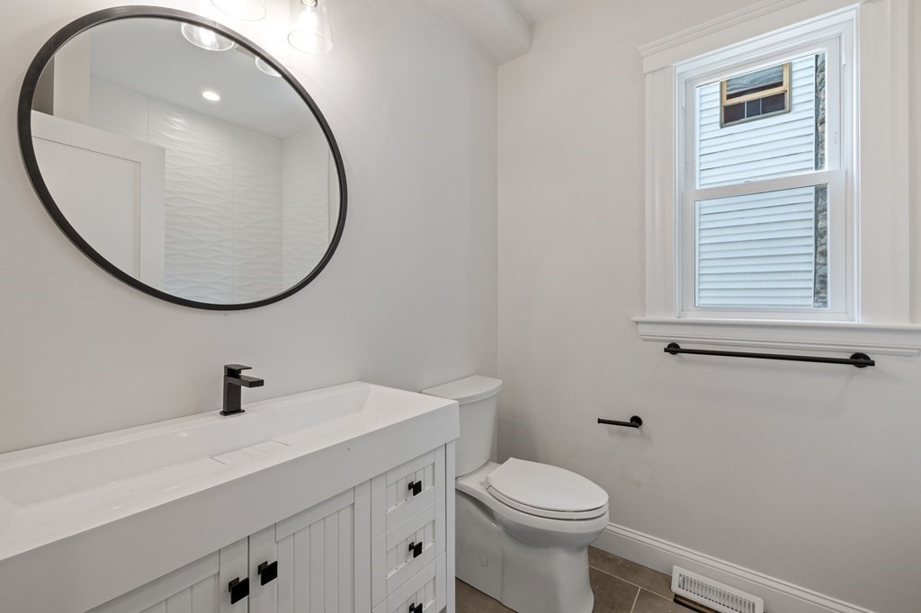 21 Alpha Road, Unit 1 Boston, MA 02124 - Photo 19 of 24 a bathroom with a sink a mirror a toilet and a window