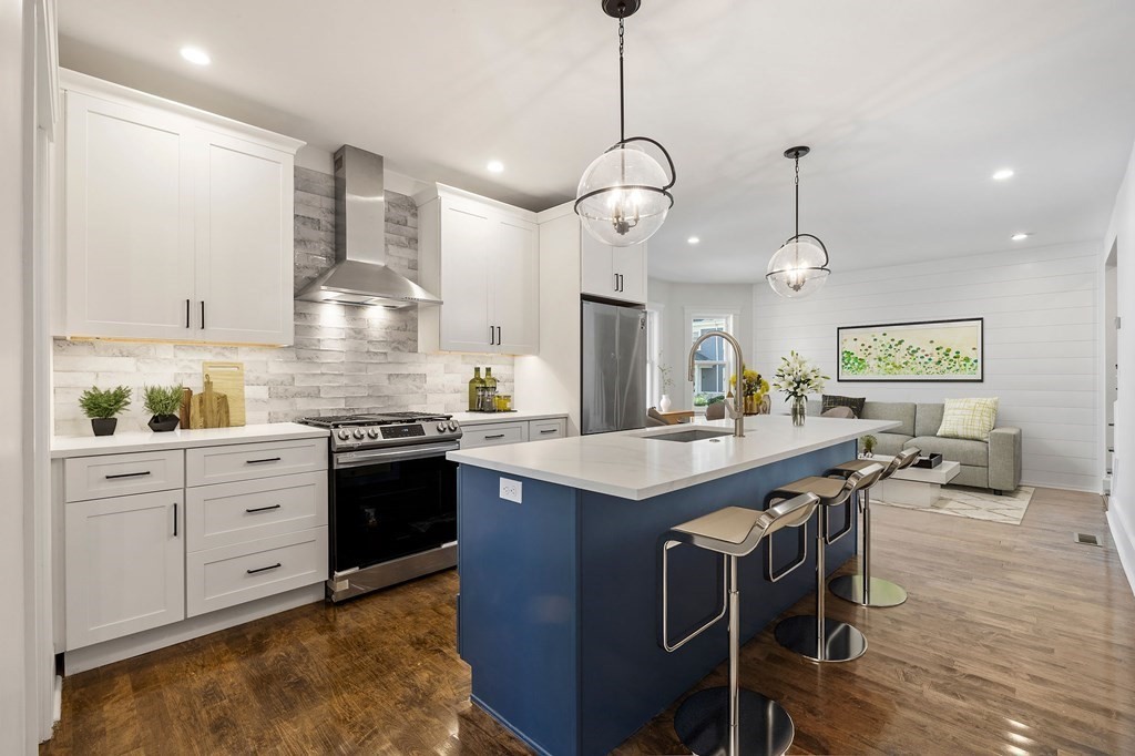 21 Alpha Road, Unit 1 Boston, MA 02124 - Photo 5 of 24 a kitchen with stainless steel appliances granite countertop wooden cabinets a stove a sink a dining table and chairs with wooden floor