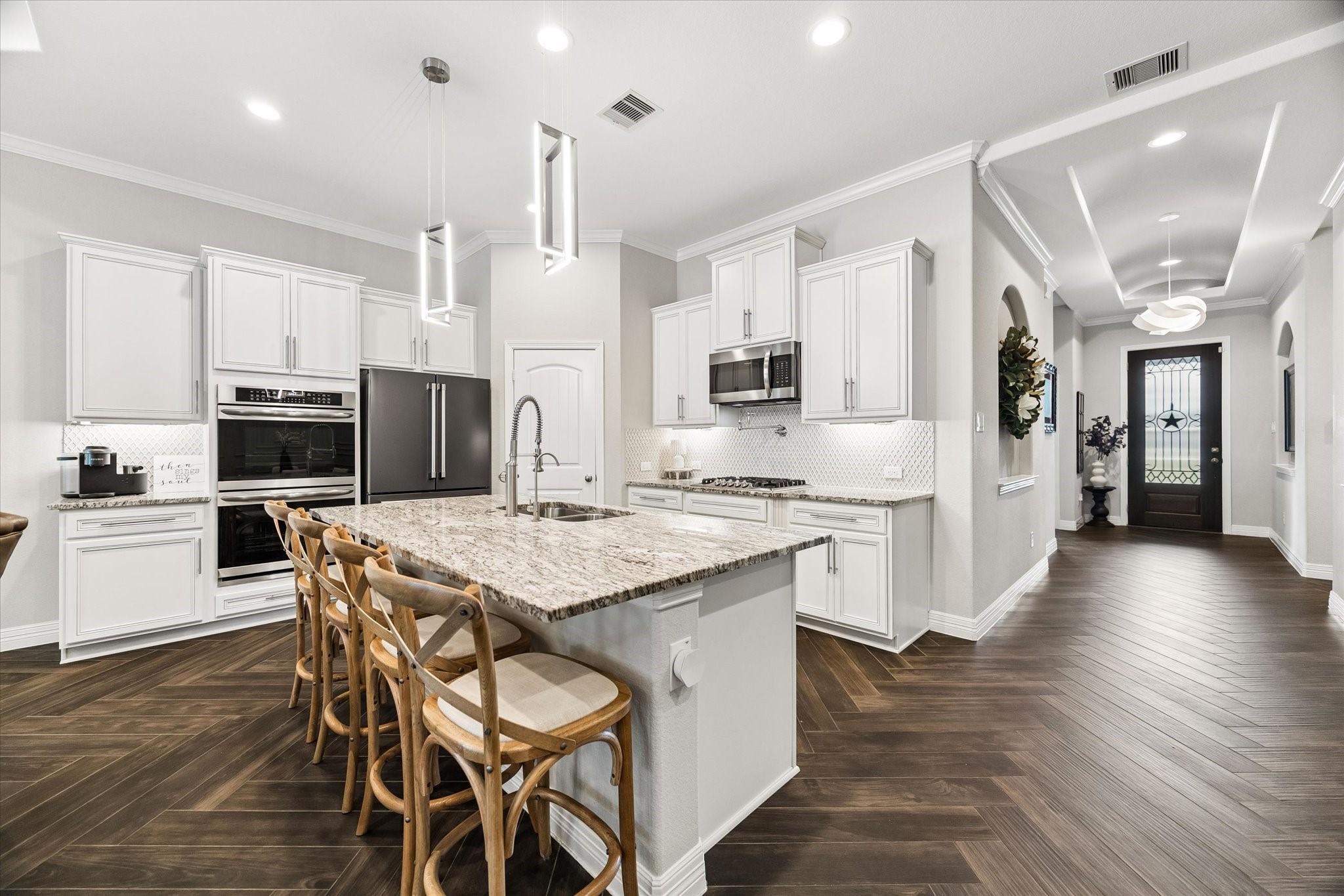 5935 Dovershire Knoll Court Spring, TX 77389 - Photo 7 of 34 a kitchen with stainless steel appliances kitchen island granite countertop a wooden floor and white cabinets